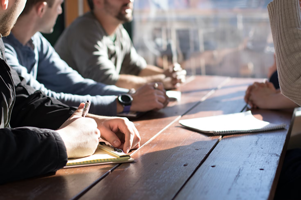 People sitting at a table taking notes during a meeting.